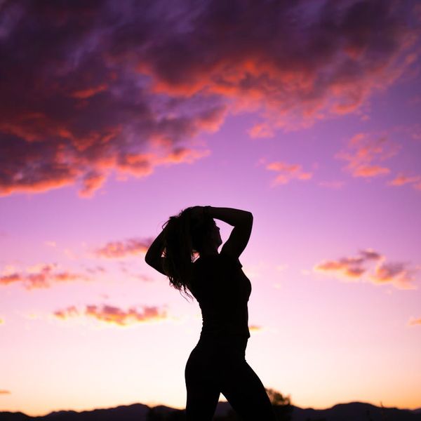 Silhouette of a person in a yoga pose against a vibrant sunrise.